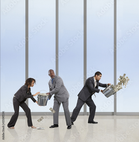 Photo: Business people bailing money with buckets Business people bailing money with buckets