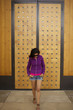 Hispanic woman standing near wooden door