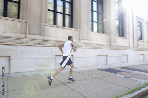 Photo: African American man running on city sidewalk African American man running on city sidewalk