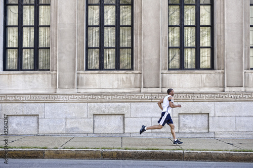 Photo: African American man running on city sidewalk African American man running on city sidewalk