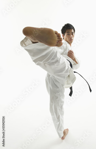 Photo: Asian male karate black belt kicking in air Asian male karate black belt kicking in air