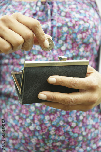 Photo: Mixed race woman putting coin in purse Mixed race woman putting coin in purse
