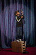 Black boy on crate singing into microphone