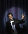 Smiling Black man in tuxedo standing at microphone