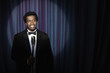 Smiling Black man in tuxedo standing at microphone