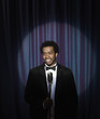 Smiling Black man in tuxedo standing at microphone