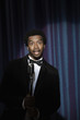 Smiling Black man in tuxedo standing at microphone
