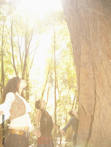 Photo: People holding hands around large tree People holding hands around large tree