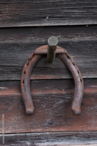 Photo: Rusted horseshoe hanging on wooden wall Rusted horseshoe hanging on wooden wall