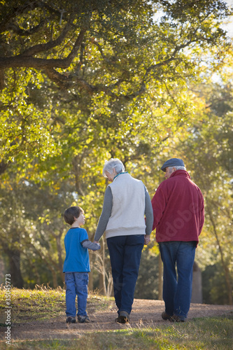 Photo: Grandparents walking with grandson in park Grandparents walking with grandson in park