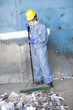 Black sanitation worker sweeping garbage at recycling plant