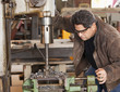 Mixed race machinist working on drill press