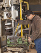 Mixed race machinist working on drill press