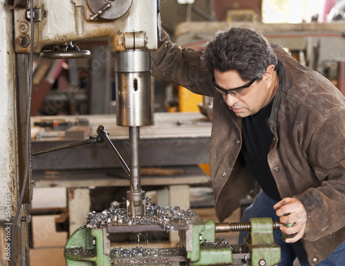 Foto: Mixed race machinist working on drill press Mixed race machinist working on drill press