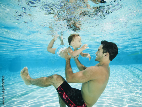 Foto: Father swimming underwater with daughter in swimming pool Father swimming underwater with daughter in swimming pool