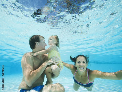Photo: Parents swimming in swimming pool with daughter Parents swimming in swimming pool with daughter