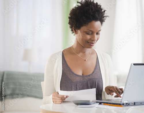 Photo: Black woman paying bills on computer Black woman paying bills on computer