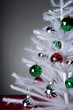 "Ornaments on white, artificial Christmas tree"