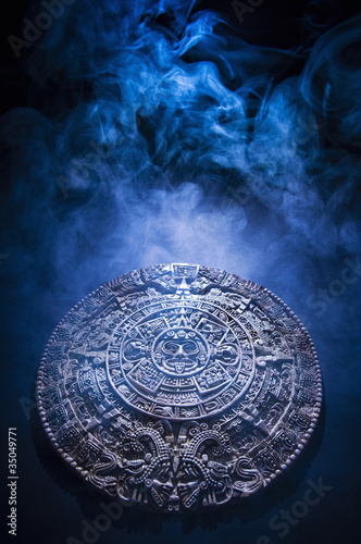 Foto: Aztec calendar stone carving surrounded by smoke Aztec calendar stone carving surrounded by smoke