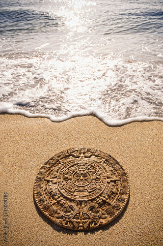 Photo: Aztec calendar stone carving on sandy beach Aztec calendar stone carving on sandy beach