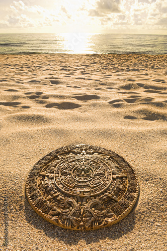Foto: Aztec calendar stone carving on sandy beach Aztec calendar stone carving on sandy beach