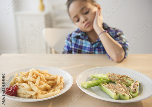 Foto: African American girl looking at healthy and unhealthy food African American girl looking at healthy and unhealthy food