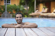 Hispanic man leaning on edge of swimming pool