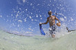 Hispanic man walking in water with snorkel gear