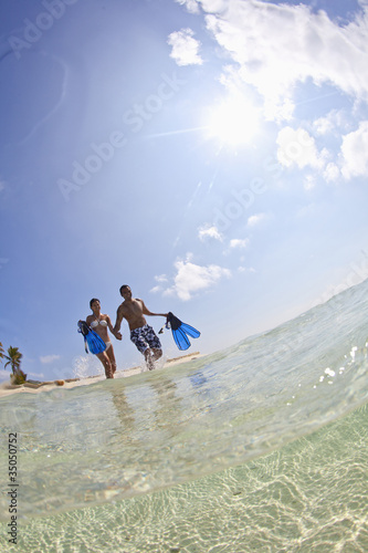 Photo: Couple wading in ocean carrying snorkeling gear Couple wading in ocean carrying snorkeling gear