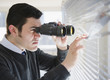 Photo: Hispanic businessman peering through window with binoculars Hispanic businessman peering through window with binoculars