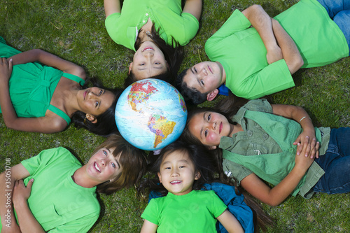 Photo: Children laying in grass around globe Children laying in grass around globe