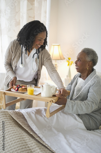Photo: Nurse serving woman breakfast in bed Nurse serving woman breakfast in bed