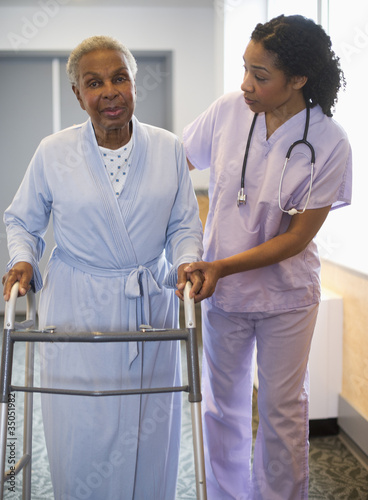 Photo: Nurse helping woman use walker in hospital hallway Nurse helping woman use walker in hospital hallway