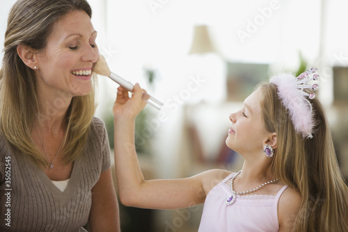 Foto: Caucasian girl putting makeup on mother Caucasian girl putting makeup on mother