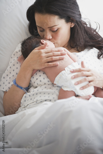 Photo: Mother in hospital bed holding newborn baby girl Mother in hospital bed holding newborn baby girl