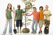 Children standing together with sapling tree and shovels