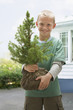 Caucasian boy holding sapling tree