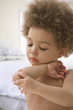 Mixed race boy touching wound on elbow