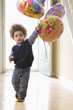 Mixed race boy holding birthday balloons