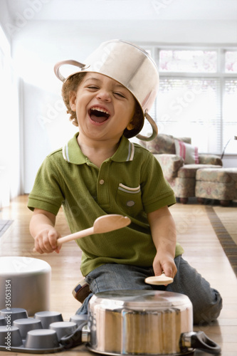 Foto: Mixed race boy beating on kitchen pots Mixed race boy beating on kitchen pots
