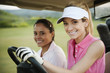 Women driving golf cart on golf course