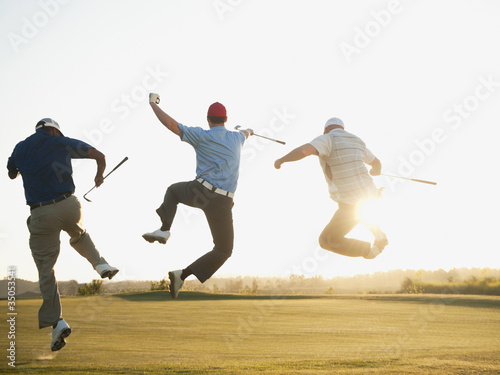 Photo: Excited golfers jumping in mid-air on golf course Excited golfers jumping in mid-air on golf course