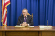 Hispanic politician sitting at desk with American flag