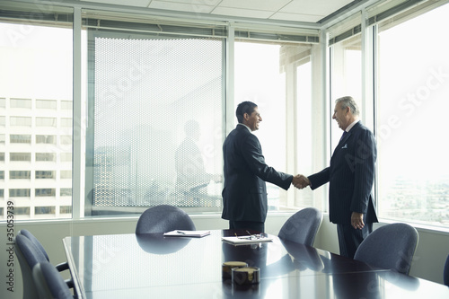 Photo: Hispanic businessmen shaking hands in conference room Hispanic businessmen shaking hands in conference room