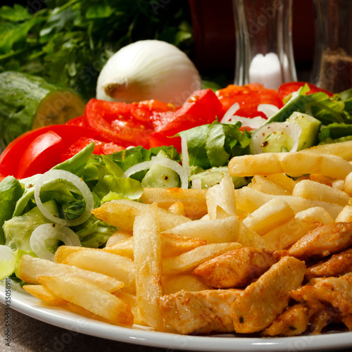 Photo: Grilled meat with French fries and vegetables Grilled meat with French fries and vegetables