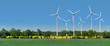 Windkrafträder in einem Rapsfeld hinter einer Allee
