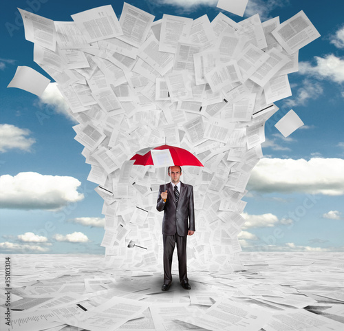 Photo: Businessman with red umbrella under huge wave of documents Businessman with red umbrella under huge wave of documents