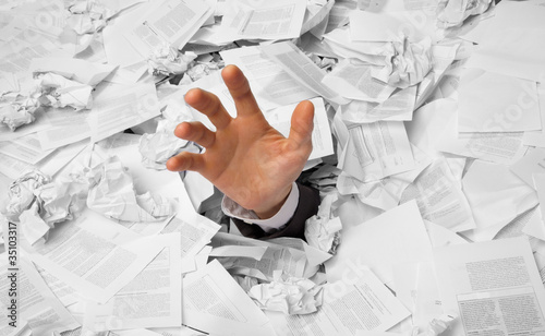 Photo: Hand reaches out from crumpled papers Hand reaches out from crumpled papers