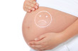 Schwangere Frau mit traurigem Gesicht auf Babybauch