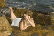 chica tumbada en las rocas junto al mar